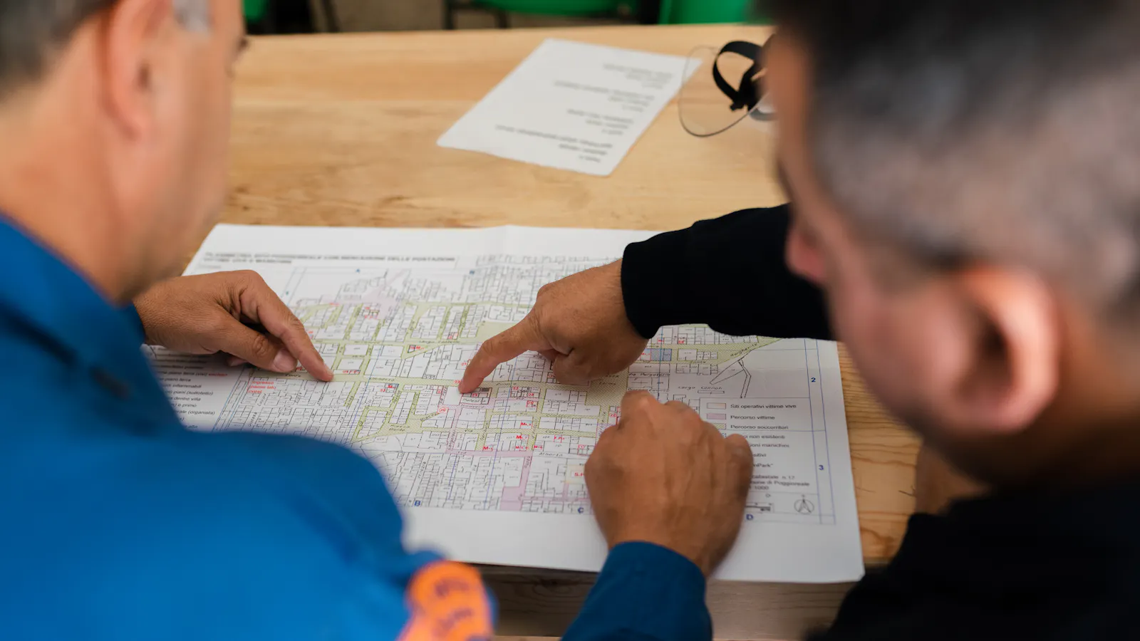 Two engineers in uniforms reviewing printed project plans